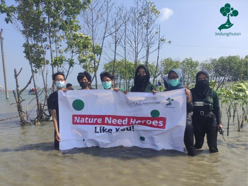 Peserta penanaman pohon berfoto dengan banner Carl & Claire.